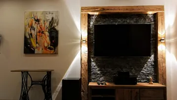 Gemütlicher Wohnbereich mit modernem TV-Möbel, Steinwand und indirekter Beleuchtung.