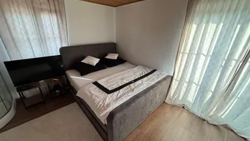Gemütliches Schlafzimmer mit Holzboden und -decke, ausgestattet mit einem bequemen Bett und Balkonzugang.