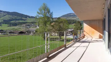Unfertiger Balkon mit Metallgeländer und weitem Blick auf die grüne Landschaft und Berge.