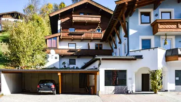 Ansicht des Gebäudes im alpinen Stil mit Holzverkleidung, Balkonen und einem überdachten Carport.