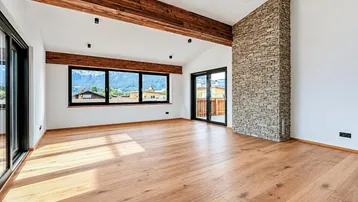 Geräumiges Wohnzimmer mit Holzbalken, Steinwand, Eichenparkett und weitem Bergblick.