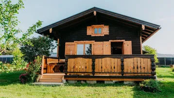 Charmantes Holzchalet mit traditioneller Architektur und kleiner Veranda im Grünen.