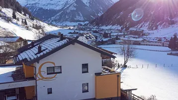 Modernes Haus in verschneiter Alpenlandschaft mit strahlendem Sonnenschein und Bergblick.