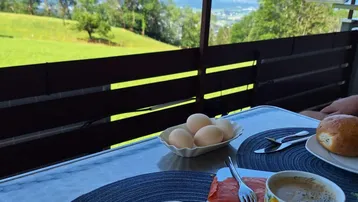Frühstück auf dem Balkon mit atemberaubendem Blick auf die Berge und grüne Landschaft.