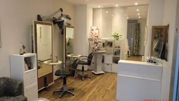 Heller Friseursalon mit mehreren Bedienplätzen, Holzfußboden und Empfangsbereich, modern eingerichtet.