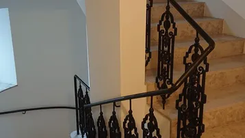 Elegantes Treppenhaus mit kunstvollem schmiedeeisernem Geländer und hellen Marmorstufen.