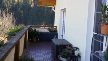 Geräumige Terrasse mit Holzbodenfliesen und Blick auf die bewaldeten Hügel.