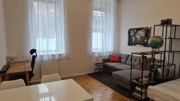 Helles Wohnzimmer mit Parkettboden, Sofa, Esstisch und Arbeitsbereich, ideal für ein Studio-Apartment.