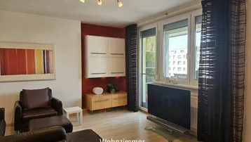 Helles Wohnzimmer mit braunen Ledermöbeln, roter Akzentwand und Blick nach draußen.