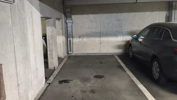 Geräumiger Parkplatz in einer Tiefgarage mit robusten Betonstrukturen und sichtbaren Installationen.