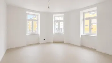 Helles, leeres Zimmer mit drei Fenstern und weiß gestrichenen Wänden, bereit zur individuellen Gestaltung.