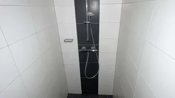 Moderne Duschkabine mit schwarz-weißen Fliesen und integrierter Duscharmatur, ideal für den täglichen Gebrauch.
