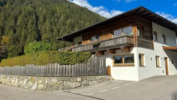 Traditionelles Haus im alpinen Stil mit Holzbalkonen und Blick auf die umliegende Berglandschaft.