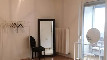 Helles Zimmer mit Fischgrätparkett, großem Spiegel und Zugang zum Balkon.