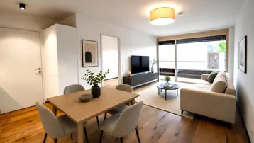 Heller Wohn- und Essbereich mit modernem Mobiliar, Holzboden und Zugang zu einem Balkon.