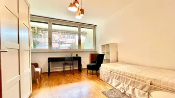 Helles Schlafzimmer mit Parkettboden, großem Fenster und modernem Deckenlicht.