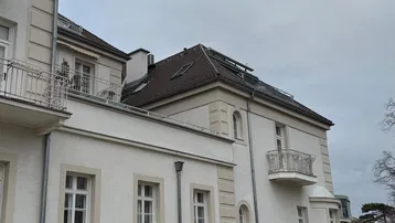 Ansicht der eleganten Gebäudefassade mit Steinverkleidung im Erdgeschoss und Balkonen.