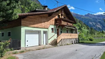 Traditionelles Haus in den Bergen mit Holzfassade, Steinsockel und Garage.