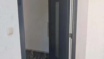 Moderner Eingangsbereich mit dunklem Marmorboden und einer stilvollen Eingangstür.