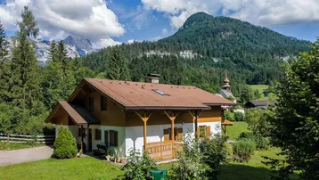 Traditionelles Haus in alpiner Landschaft mit Bergblick und viel Grün.