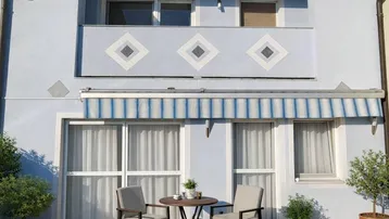 Gemütliche Terrasse mit Sitzgelegenheiten und Markise vor der hellblauen Hausfassade.