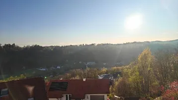Weitläufiger Blick über die grüne Landschaft mit Häusern und viel Sonne.