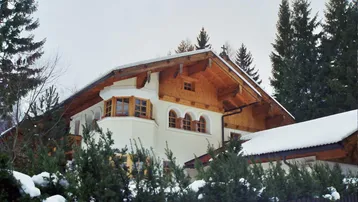 Traditionelles Haus mit Holzelementen, schneebedecktem Dach und alpiner Architektur.