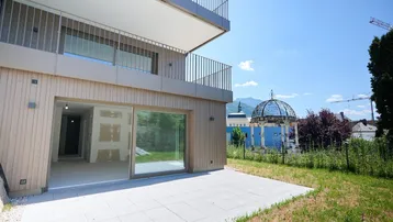 Moderne Terrasse mit Zugang zum Garten und Blick auf eine historische Kuppel und Berge.