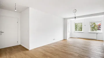 Helles, leeres Zimmer mit Parkettboden und weißen Wänden, bereit zur individuellen Gestaltung.