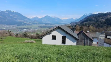 Haus in idyllischer Hanglage mit weitem Blick auf die umliegende Berglandschaft.
