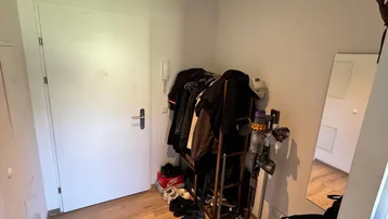 Heller Eingangsbereich mit Laminatboden, Garderobe und weißer Tür.
