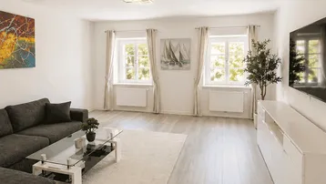 Helles Wohnzimmer mit modernem Sofa, Couchtisch aus Glas und hellem Laminatboden.