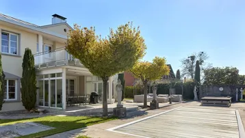 Großzügiger Gartenbereich mit Pool, Terrasse und gepflegten Bäumen hinter dem Haus.