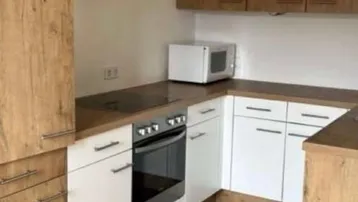 Moderne Küche mit Holz- und weißen Fronten, ausgestattet mit Backofen, Mikrowelle und Dunstabzugshaube.