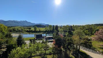 Panoramablick auf einen See mit Bergen im Hintergrund an einem sonnigen Tag.