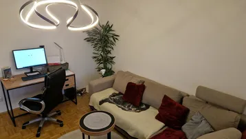 Helles Wohnzimmer mit modernem Lichtdesign, Sofa und integriertem Arbeitsbereich.