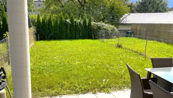 Gepflegter Gartenbereich mit Rasenfläche und einer Terrasse mit Sitzgelegenheiten für entspannte Stunden im Freien.