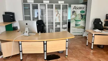 Helles Büro mit L-förmigem Schreibtisch, Computer und Regalen, ausgestattet mit Terrakottafliesen.