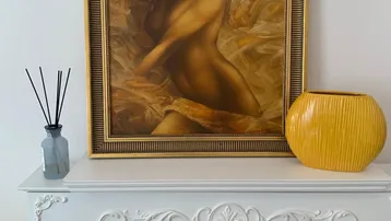 Dekorativer Kaminsims mit einem Gemälde und einer gelben Vase als stilvolle Akzente.