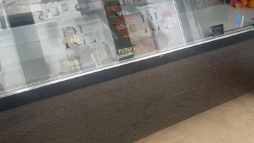 Nahaufnahme einer Verkaufstheke mit Glasvitrine und Fliesenboden in einem Geschäftsbereich.