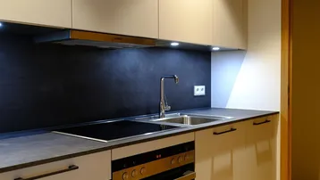 Moderne Einbauküche mit hellen Schränken, Induktionskochfeld und integriertem Backofen.