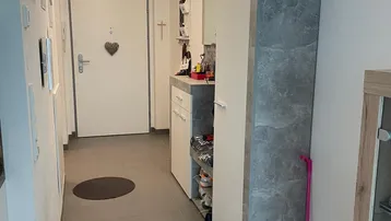 Heller Eingangsbereich mit Fliesenboden, Garderobenschrank und dekorativem Kronleuchter.