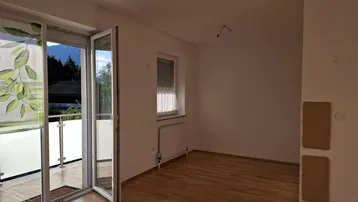Helles Zimmer mit Holzboden, weißen Wänden und direktem Zugang zu einem Balkon.
