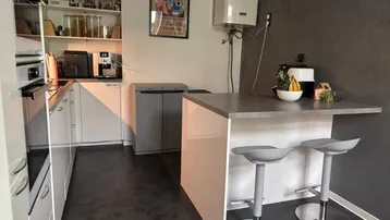 Moderne Küche mit weißen Schränken, Kücheninsel und integrierten Geräten.