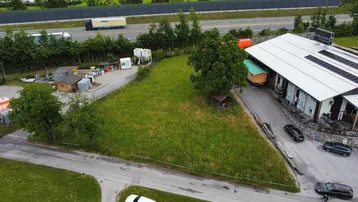 Luftaufnahme eines dreieckigen Grundstücks mit Grasfläche, angrenzend an eine Straße und eine Autobahn.
