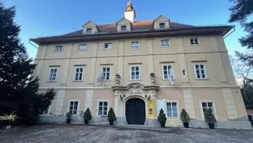 Historisches Gebäude mit gelber Fassade, vielen Fenstern und einem markanten Turm auf dem Dach.