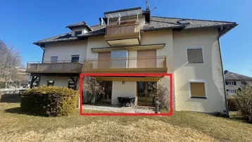 Außenansicht des Gebäudes mit einer einladenden Terrasse im Erdgeschoss, umgeben von Grünflächen.