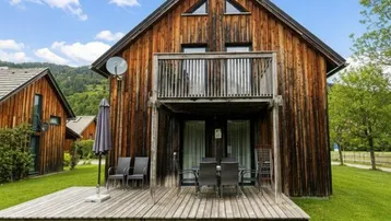 Rustikales Holzchalet mit großer Holzterrasse, Balkon und Blick auf die umliegende Berglandschaft.
