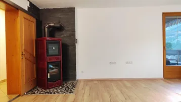 Wohnzimmer mit Holzboden und einem modernen Kaminofen als gemütliches Heizelement.