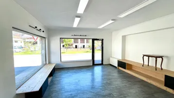 Heller, moderner Geschäftsraum mit großen Schaufenstern, Vinylboden und eingebauten Holzregalen.